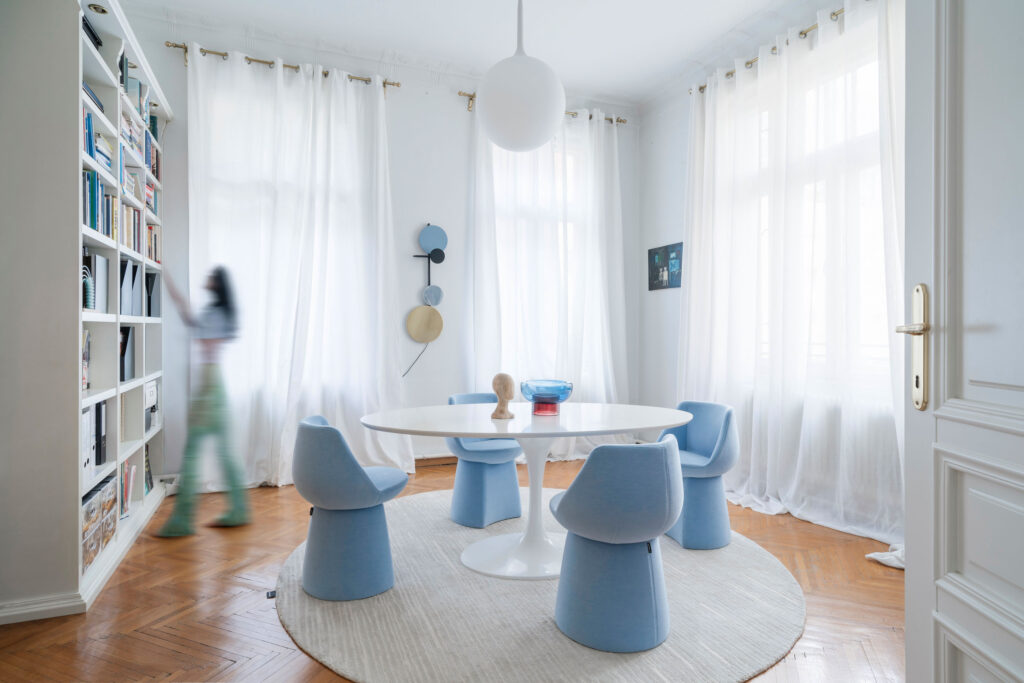 blauer Stuhl, modernes Design, minimalistischer Raum, eleganter Innenraum, organische Form, komfortabler Stuhl, Stoffbezug, runder Tisch, helles Interieur, natürliche Beleuchtung, weiche Textur, minimalistisches Mobiliar, elegantes Raumdesign, Wohnzimmermöbel,